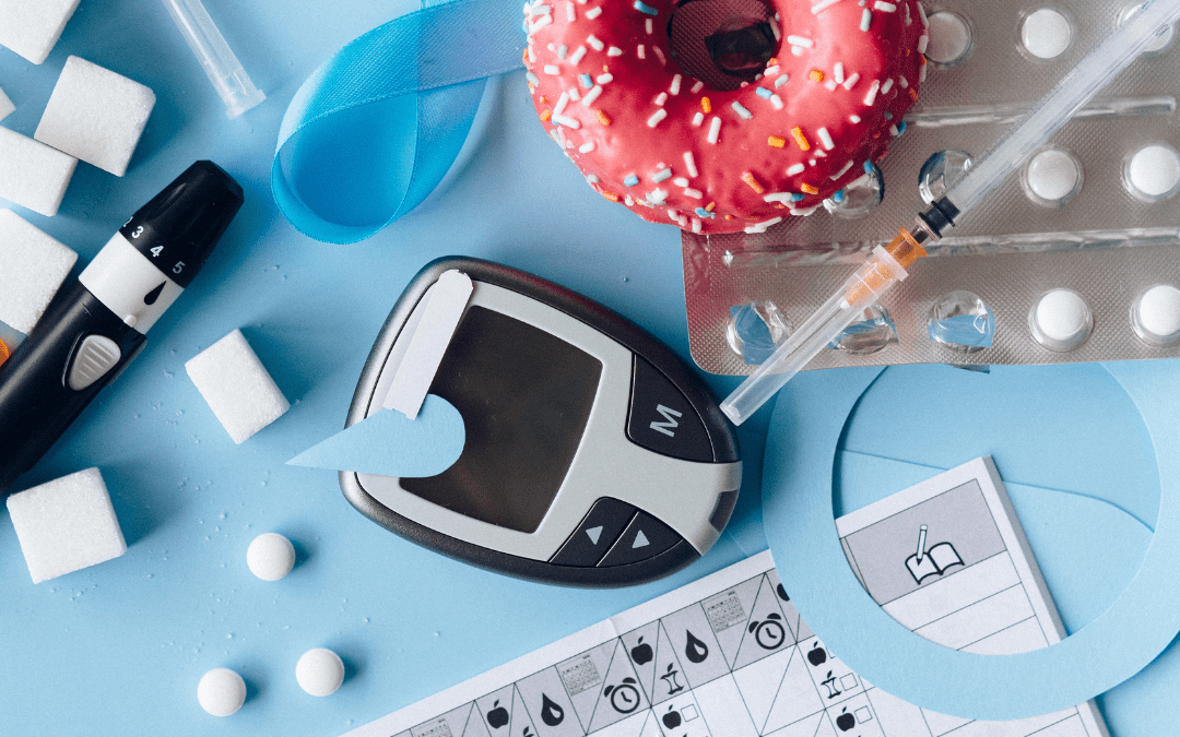 An assortment of tools needed to manage diabeties- blood sugar meter, insulin in a syringe, finger stick, as well as sugary treats like doughnuts and gummy bears.